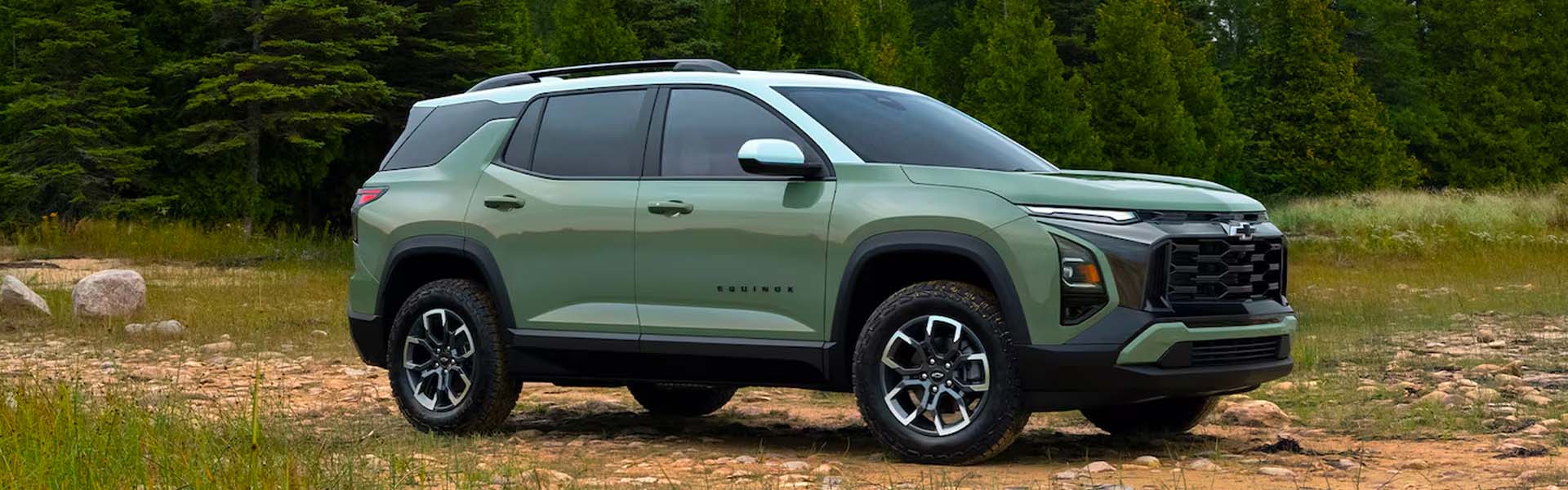 2026 Chevrolet Equinox compact SUV in matte green with black roof and alloy wheels, shown in a forest setting highlighting off-road capability and bold front grille design