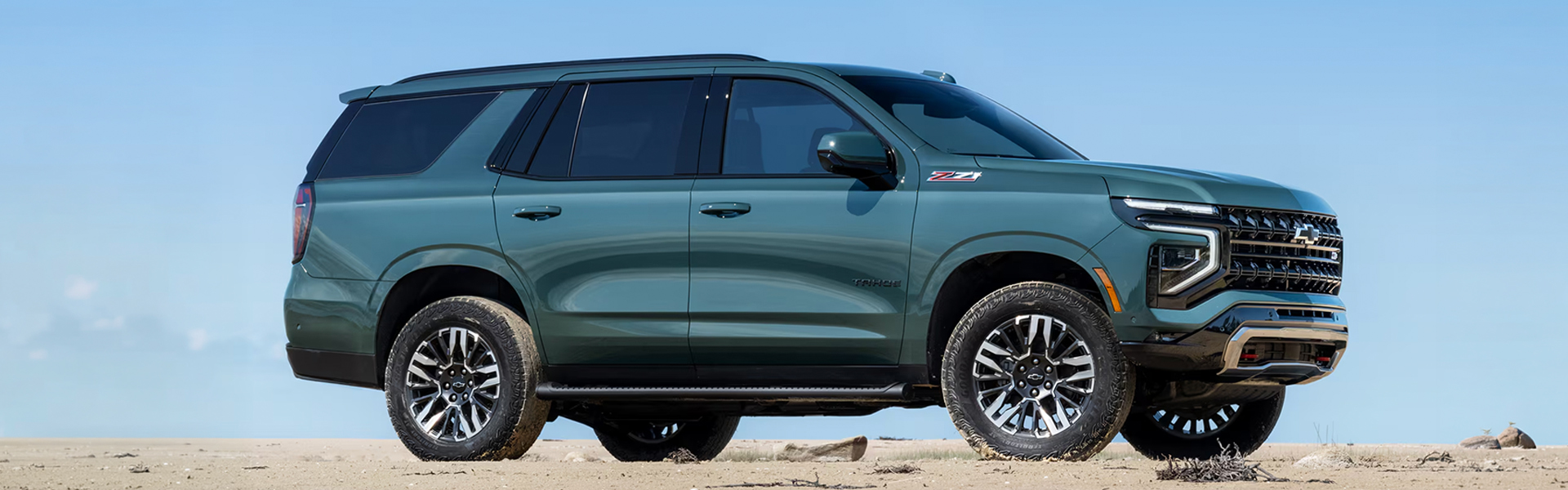2026 Chevrolet Tahoe in a sandy landscape with a clear blue sky.