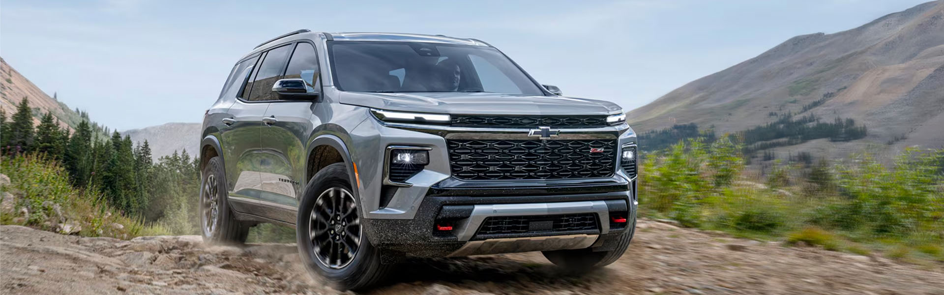 2026 Chevy Traverse Z71 midsize SUV driving on a rugged mountain trail.